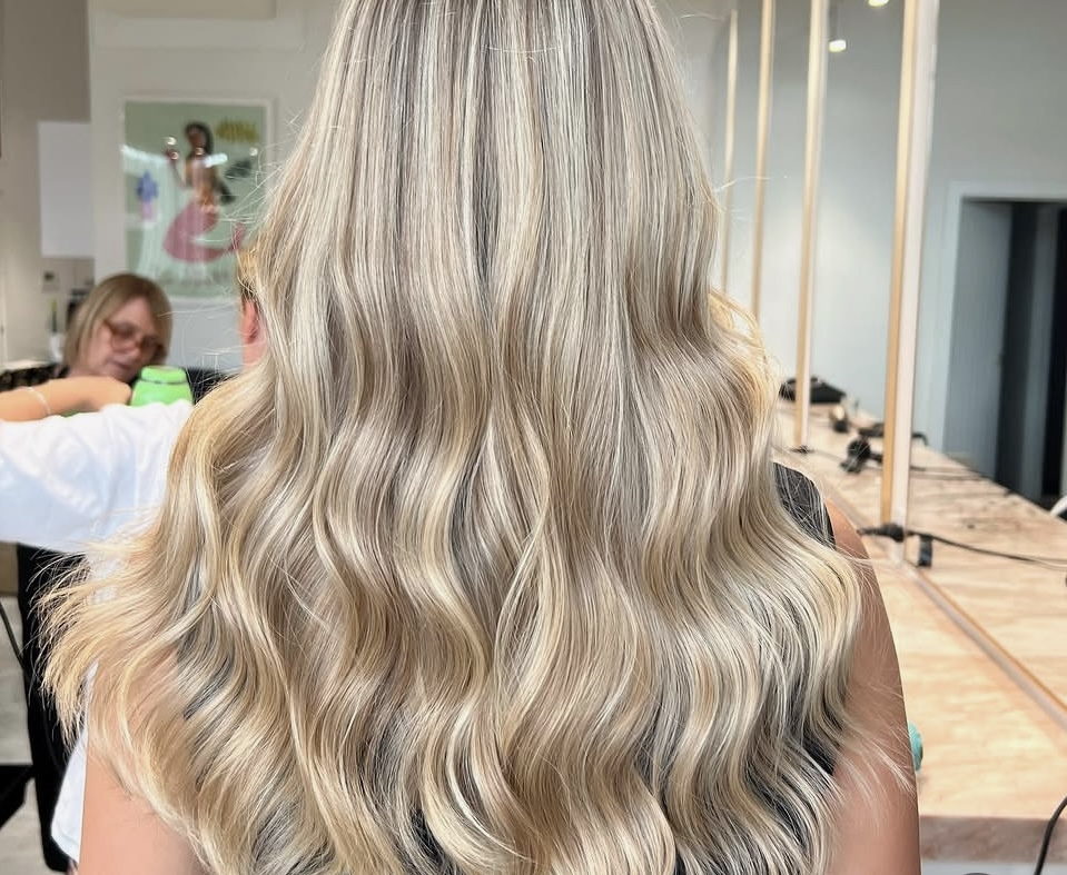 Long blonde hair with cool-toned highlights and soft waves